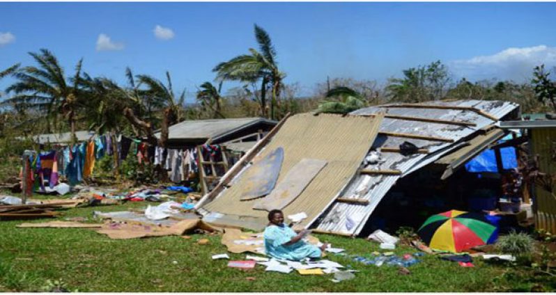 A woman sits outside her damaged home in Vanuatu's capital Port Vila following the devastating Cyclone (Photo courtesy: thestar.com)