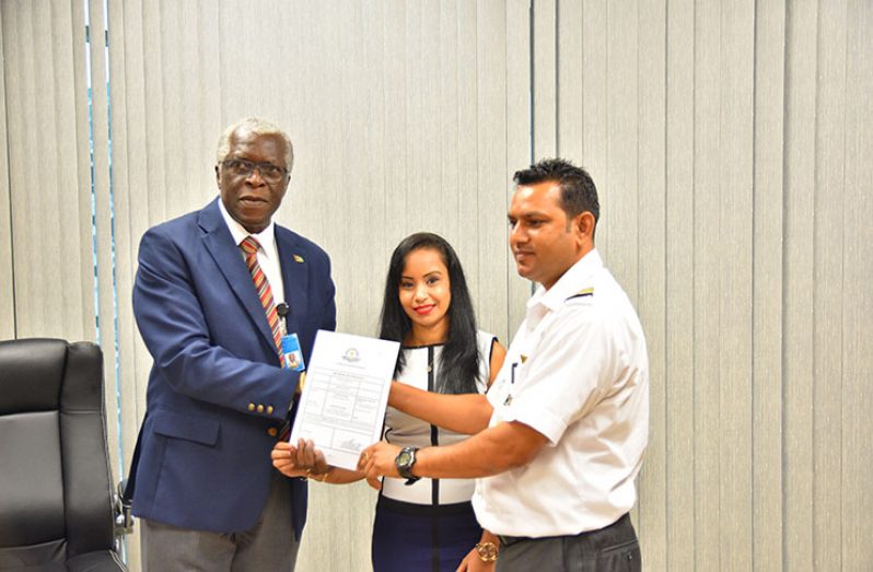 Director General of Guyana Civil Aviation Authority (GCAA), Egbert Field (first left),hands over the Air Operator Certificate (AOC) to Director of Domestic Airways, Orlando Charles (first right)  in the presence of Charles’ wife, Komaldevi Charles (center)