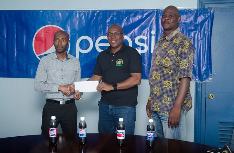 DDL’s Larry Wills (left) hands over the partnership package to GBA president Steve Ninvalle, while Technical Director Terrence Poole looks on. (Delano Williams photo)