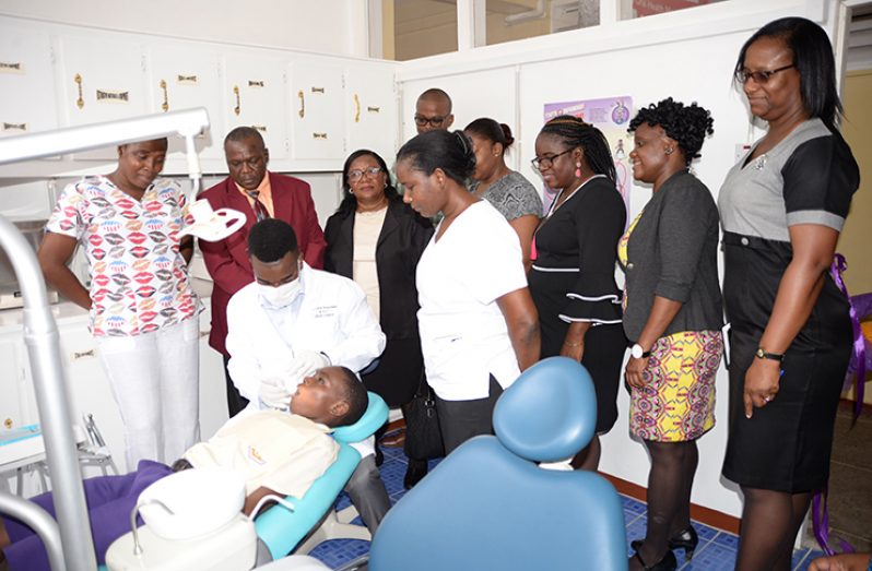 Dentist-in-residence, Dr. Collin Waterman doing an oral examination on this year’s top National Grade Six Assessment (NGSA) student, Quacy Issacs at the new centre. Among those looking on are school Principal, Carlyn Canterbury (third right), and Principal Dental Officer, Dr. Kester Sullivan, second left (Photo by Delano Williams)
