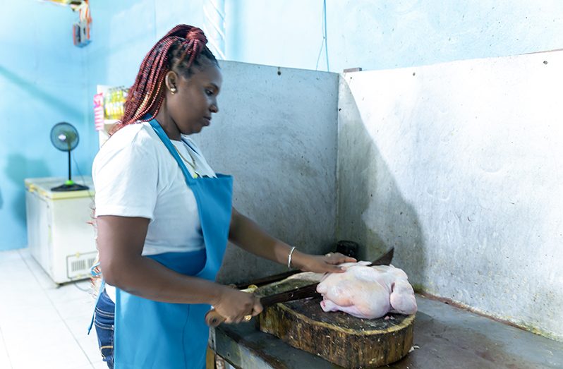 Butcher, Shenelly Inniss cutting up an 8lbs chicken in the shop