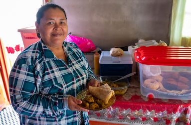 Hermilda Debideen displaying her freshly prepared roti and chicken curry at her home (Delano Williams photos)