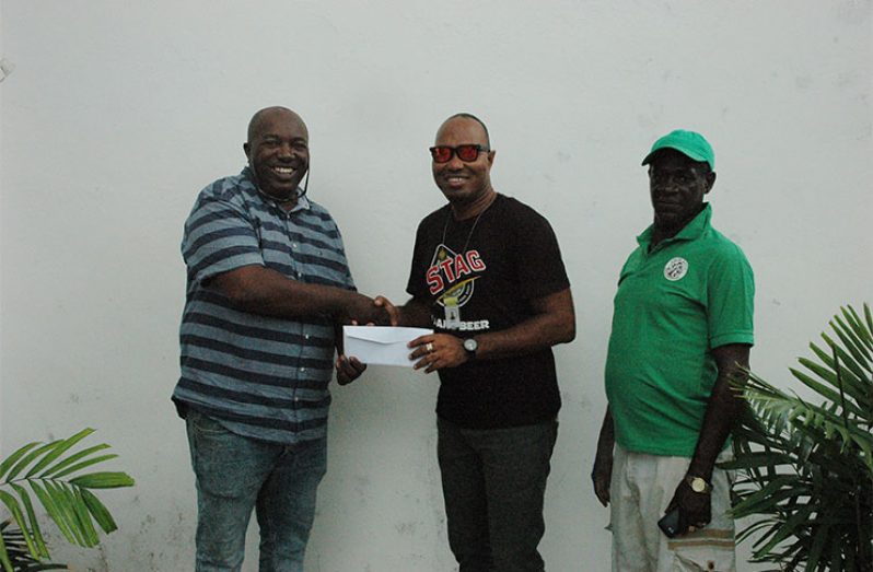 Organiser Dion Carter (left) collects a sponsorship cheque from STAG Beer’s Brand Manager Nigel Worrell as Mark ‘Jumbie’ Wiltshire looks on.