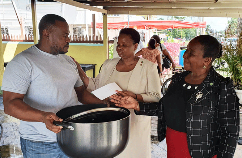 Chairman of the People's National Congress Reform (PNCR), Volda Lawrence makes a donation to the Guinness Bar and Restaurant owner, Troy Mendonca