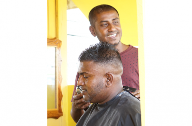 Chaitnauth Raghubir
called ‘Vicky’ with
a customer in his
small barber shop at
Stelling Road