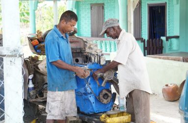 Shameer Baksh and his son fixing the engine of a tractor