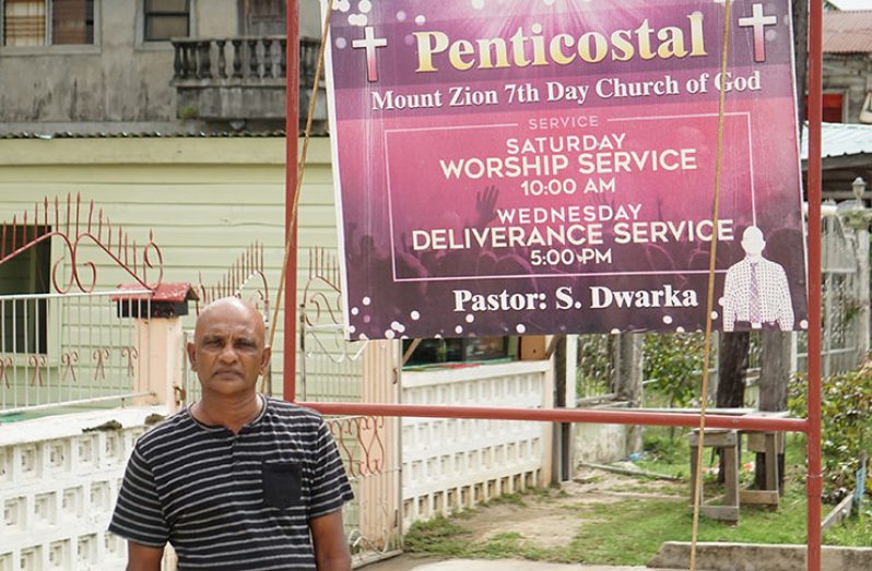 Pastor Seecharran Dwarka by his church signboard (Carl Croker photos)