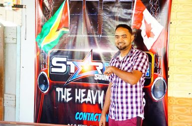 Teacher Gregory Gunraj poses by the Starlite Heavy Hard Hitters Sound the business he is attached to as a DJ