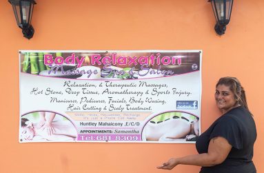 Samantha Thaknauth poses in front of her business poster at her shop in Huntley, Mahaicony (Japheth Savory photos)