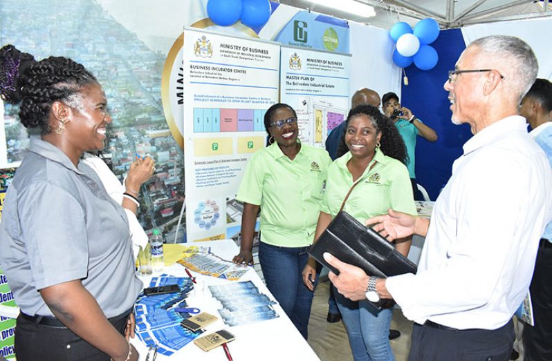 Director of Business, Dominic Gaskin, speaks with staff at the Ministry of Business booth during the Berbice Expo on Friday