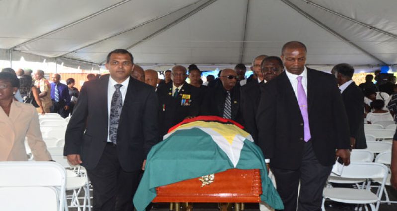 Minister of Culture, Youth and Sport, Dr. Frank Anthony (left) and Permanent Secretary Alfred King (right), among those bearing the body of Col Lindon Ross out of the Cliff Anderson Sports Hall compound on Wednesday