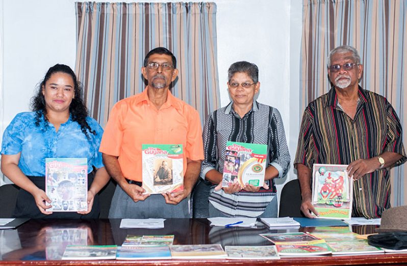 Guyenterprise staffer Danielle Swain, Editor of “The Guyana Annual” Petamber Persaud, Shamshun Mohamed and Allan Fenty display older editions of the magazine.