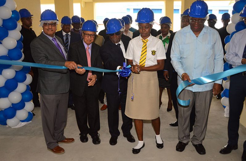 Queen’s College Sixth Form student, Leshanna Bindah assists Finance Minister Winston Jordan (extreme right), in cutting ceremonial ribbon at the new DSL warehouse. From left are DDL Executive Chairman Komal Samaroo; iconic business executive, Dr. Yesu Persaud and Minister of Foreign Affairs, Carl Greenidge (Adrian Narine photo)