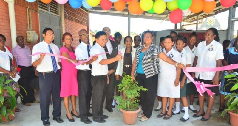 The generator is turned on as Clive Chin, Jnr.  cuts the ceremonial ribbon. Behind him is Mr. John Seeram.  Others from left are  First Counsellor Clive Hugh and Mrs. Chin and  Elder W. Barrow.  Holding the other end of the ribbon is Principal Penelope Harris
