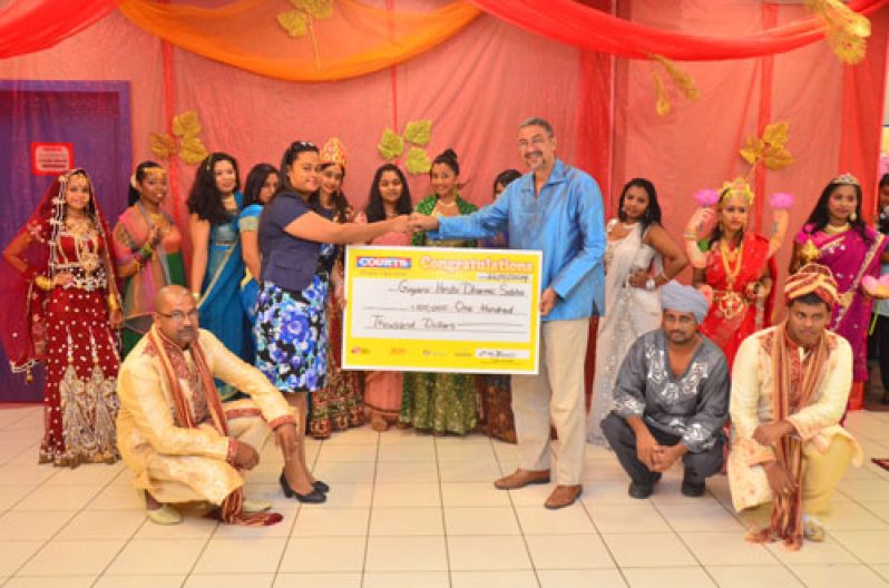 Managing Director of Courts (Guyana), Clyde De Haas and Ms. Seeram of the Guyana Hindu Dharmic Sabha during the symbolic cheque handing over