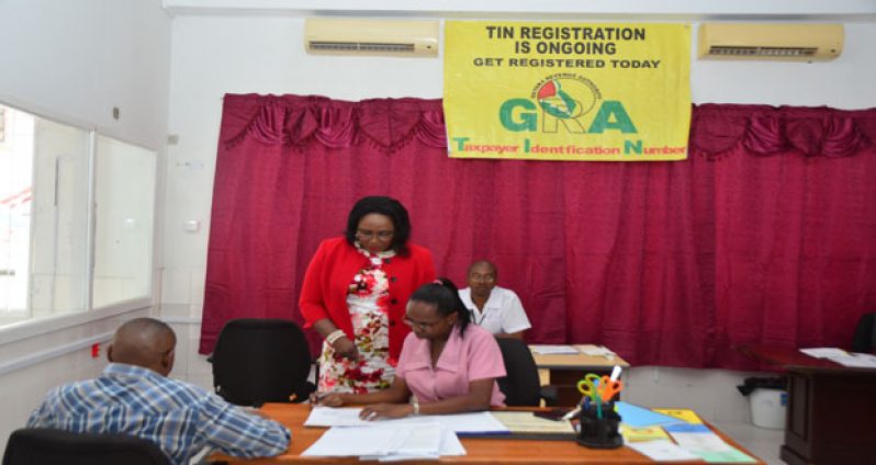 Karen Chapman - Deputy Commissioner, Law Enforcement and Investigation Division (LEID) (standing) pays keen attention as one of the employees attend to a tax payer.