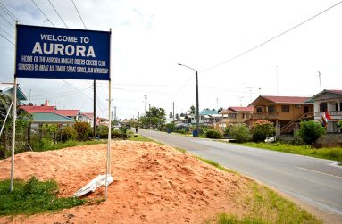 The village signage is prominently displayed on the public road at Aurora Estate