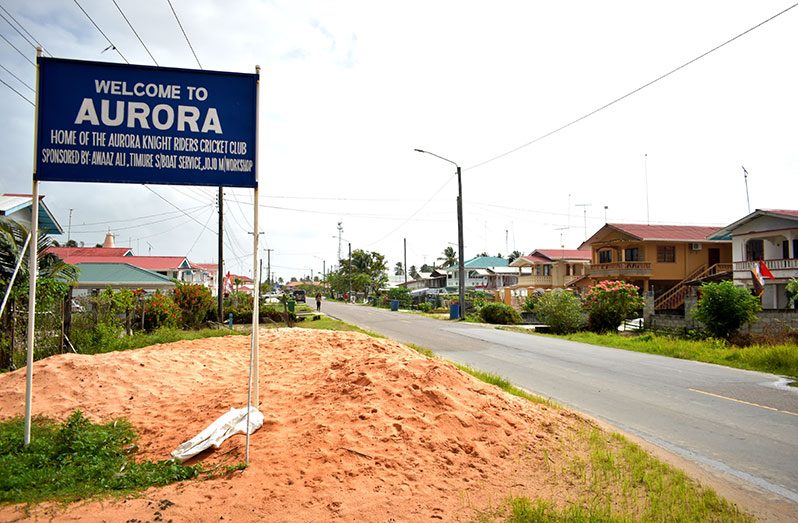 The village signage is prominently displayed on the public road at Aurora Estate