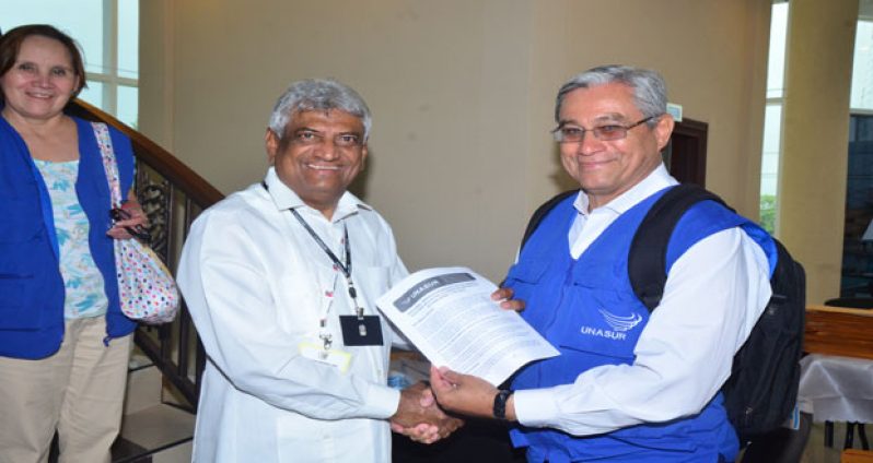 UNASUR’s Chief Mission Representative, Mr. Domingo Paredes, hands over the preliminary report to Dr. Steve Surujbally