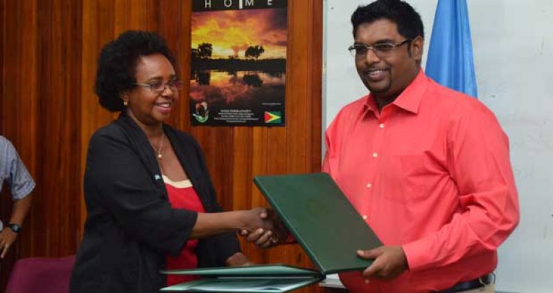 Minister of Tourism (ag) Irfaan Ali and Ms. Khadija Musa, UNDP Resident Representative hand over agreement.
