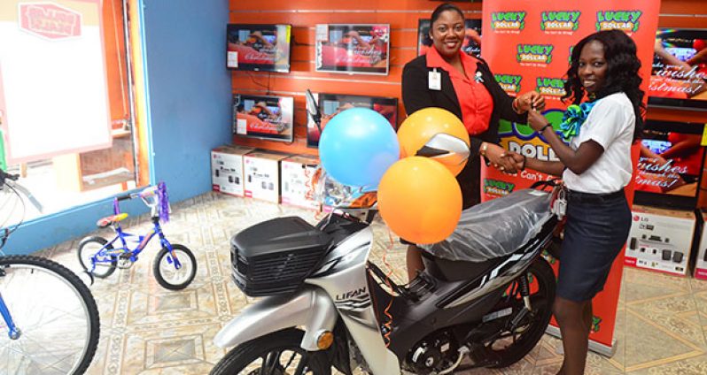 Lucky Dollar Regent Street Branch Manager, Sharon Persaud hands over keys to the motorbike to lucky customer, Lonell Joseph (Photo by Adrian Narine)