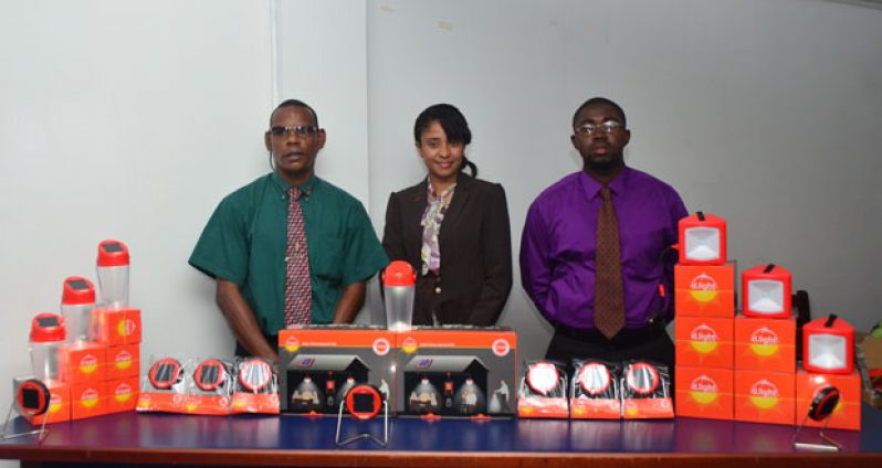 Christopher Jacques, Mrs Persaud and Dale Browne with some of the D.Light solar lighting products on display