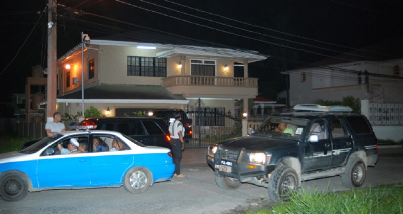 Police and GRA officers in front of Lot 8 Continental Park, East Bank Demerara, the address listed on the registration forms for both of the vehicles