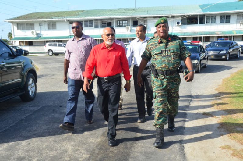 Commander-in-Chief of Guyana’s Armed Forces, President Donald Ramotar and GECOM Commissioner Sase Gunraj walk inside a Police polling place at Eve Leary, yesterday morning, as ranks look on