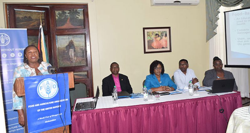 Dr Pauline Samuda, FAO Regional Consultant, addressing the gathering.  Seated, from left, are:  FAO Representative Reuben Robertson; Minister within the Ministry of Public Health, Dr Karen Cummings; Chief Medical Officer, Dr Shamdeo Persaud; and Ninian Blair, Director (Ag), Food Policy Division