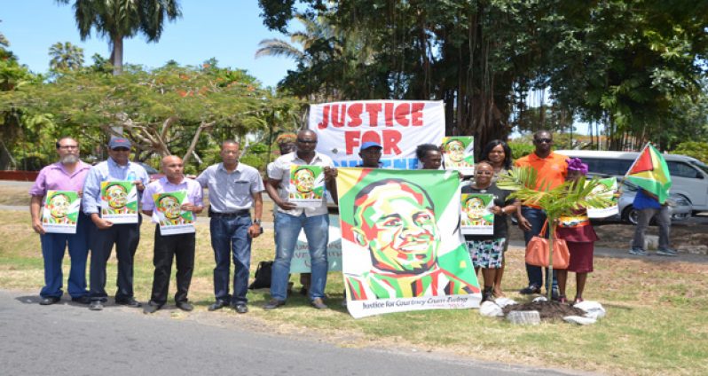 Relatives, friends and other supporters of Courtney Crum-Ewing stage a vigil to mark the 1st anniversary of his brutal slaying on March 10, 2015. The vigil was held at the corner of Middle and Carmichael Street, Georgetown.
Standing in the fore-front of banner are: Crum-Ewing’s brother, Dwayne; mother, Donna, and sister, Althea in back row (holding small portrait) .