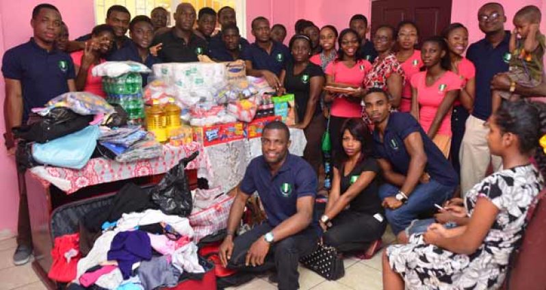 The group of Nigerian medical students during their presentation to the children of the Ministry of Human Services ‘Drop In’ Centre of Friday.  At right (lifting baby) is NiSAG President, Samuel Obiegbusi. Standing at centre (close to table of goodies)is Vice- President, Ebrys Okpako, while standing just inside the door (in floral top) is Matron of the Centre, Ms. Lynette Roberts (Photo by Adrian Narine)