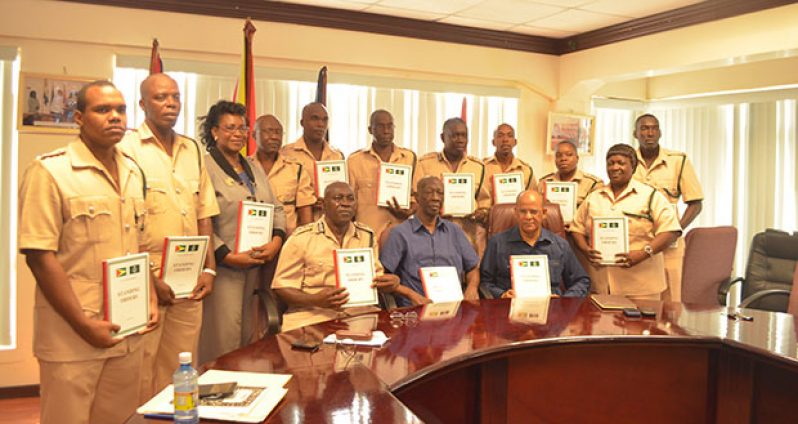Seated in front row are Home Affairs Minister, Clement Rohee; Head of the Standing Orders Committee, Mr. Cecil Kilkenny; and Director of Prisons, Mr. Welton Trotz, who are flanked by senior officers of the GPS, displaying copies of the Standing Orders (Cullen bess-nelson photo)