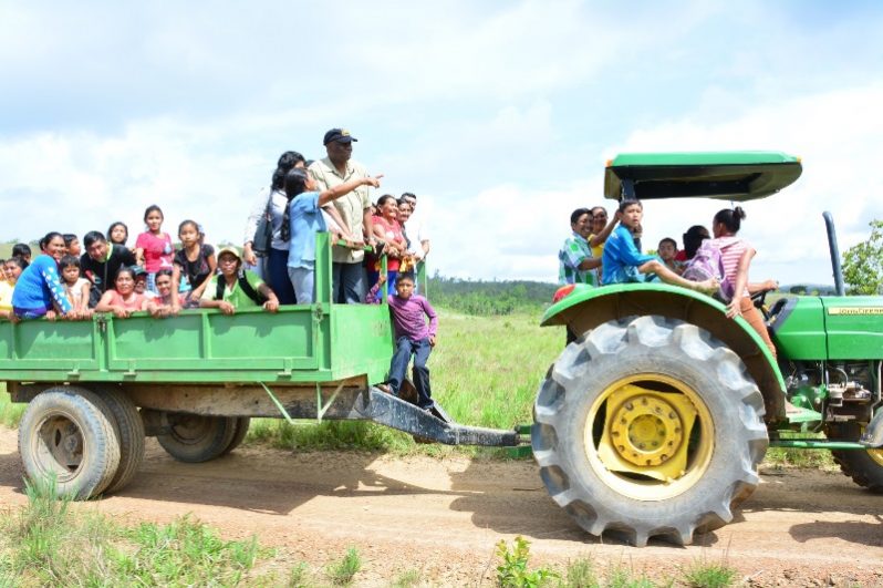 Minister Harmon being taken through the village of Itabac in a tractor by residents, to examine the damages which were caused by the flash flooding due to the overtopping of the Ireng River.