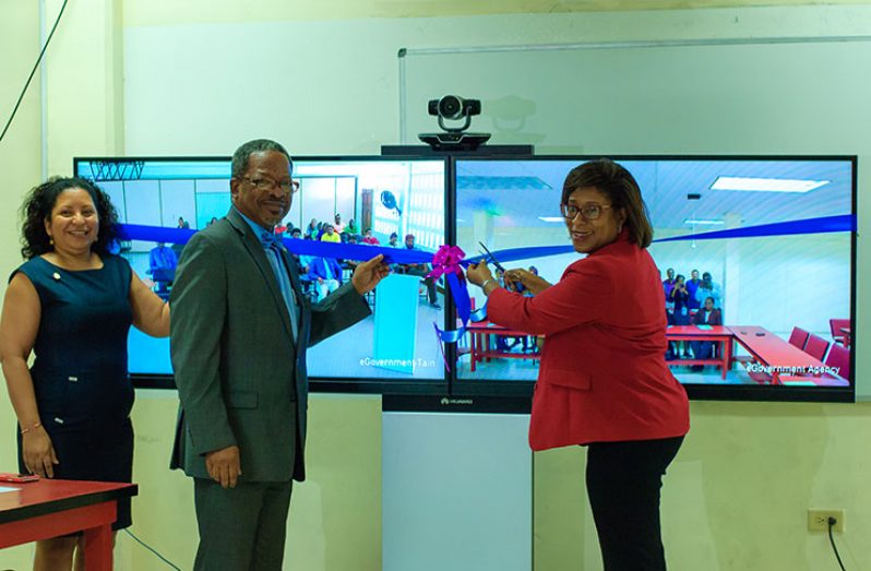 Minister of Public Telecommunications, Ms Cathy Hughes cuts the ceremonial ribbon to mark the commissioning of the teleconferencing suite. Helping her do the honours are, from left: Deputy Vice-Chancellor, Dr Paloma Mohamed, and Vice- Chancellor, Dr Ivelaw Griffith