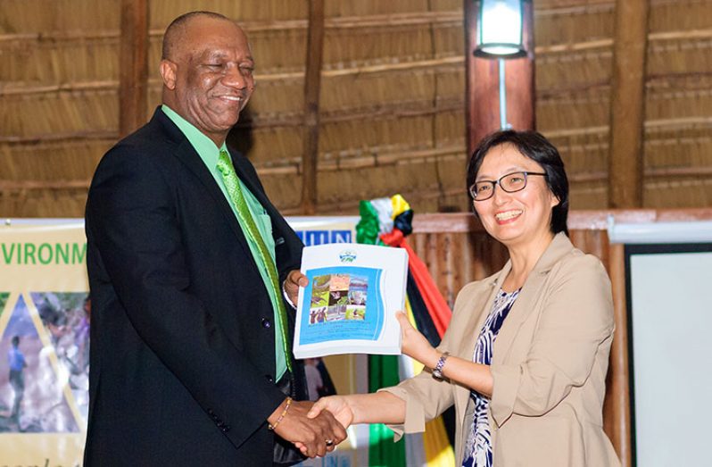 Minister of State Joseph Harmon receives a copy of the Guyana State of the Environment Report from United Nations Resident Representative, Mikiko Tanaka (photo by Delano Williams)