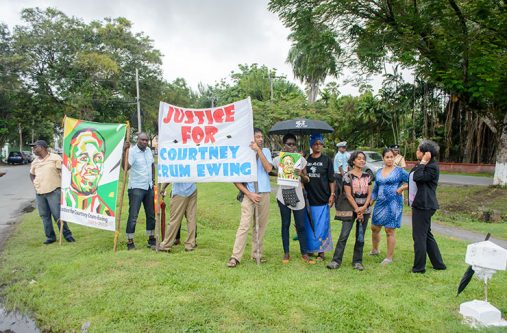Protestors cry “Justice for Courtney Crum-Ewing” outside the Chambers of the Attorney General and Ministry of Legal Affairs