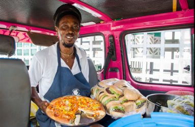 Keith Hutchins, popularly known as “Ras” poses with some of the Ital delicacies he sells on the street in his bus every day at the Rubis Gas Station on Vlissingen road, Georgetown