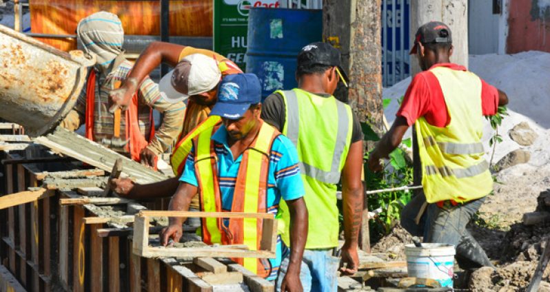 A section of the completed drain and pavement being attended to by workers