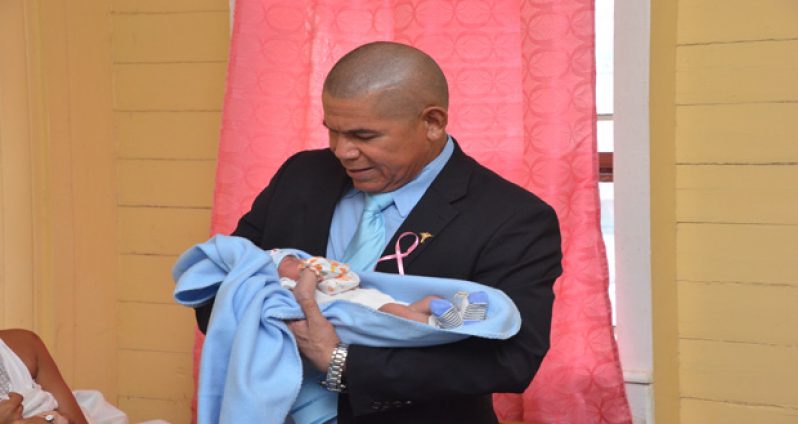 Dr. George Norton cuddles a newborn while on a walk-about at the West Demerara Regional Hospital yesterday