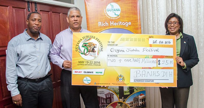 Mortimer Stewart, Outdoor Events Manager of Banks DIH, and Sales and Marketing Executive Carlton Joao of Banks DIH present the cheque to Minister Cathy Hughes