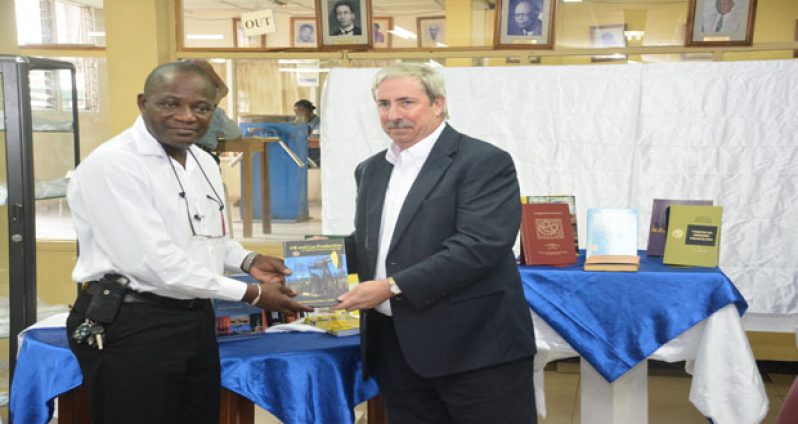 UG Vice-Chancellor, Prof. Jacob Opadeyi (left) receives the books from EEPGL Country Manager, Mr Jeff Simons