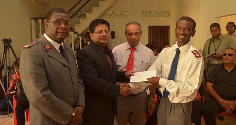Finance Minister, Dr. Ashni Singh hands over the cheque to Major Emmerson Cummberbatch. Looking on is Chairman of the Advisory Board, Edward Boyer and Administrator Major Urick Thibaud