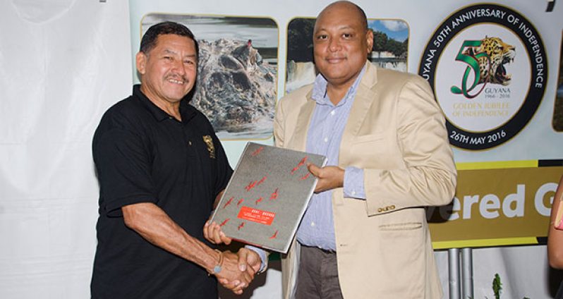 Minister Trotman hands a copy of the book to Minister of Indigenous People’s Affairs, Sydney Allicock (Photo by Delano Williams)