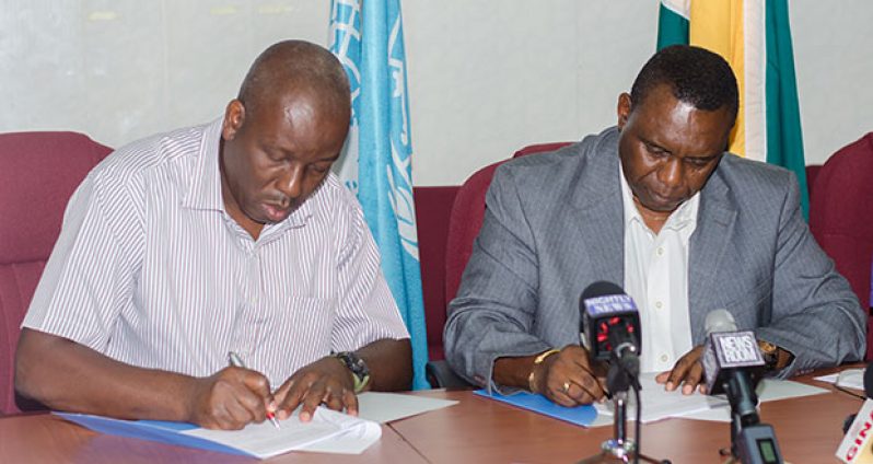 Permanent Secretary of the Ministry of Agriculture, George Jervis (left), and FAO Country Representative Reuben Hamilton Robertson, sign the agreement for the US$500,000 project to support the local fisheries industry