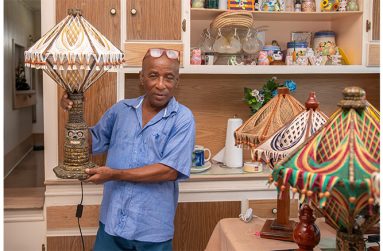 Claudius Henry poses with one of his hand-made lamps