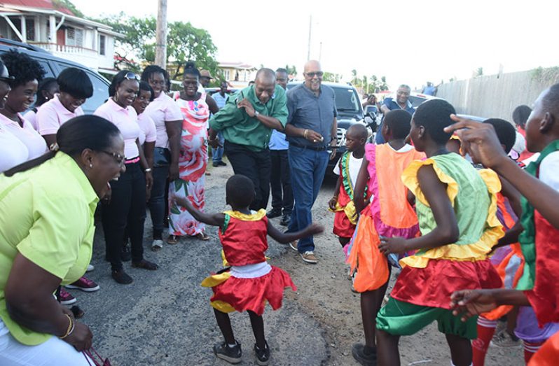 Minister Simona Broomes watches on with excitement as Minister of State, Joseph Harmon, shows off his moves with a young masquerader on a streets in Ann's Grove