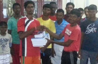 PMCC Under-17 skipper Daniel Samaroo (forefront right) is all smiles as he accepts his textbooks from Yogendra Harrinarine, in the presence of other club members.