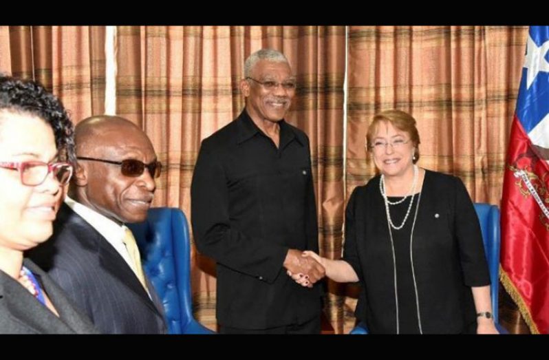 Guyana’s President David Granger and Chile’s President Michelle Bachelet shake hands during their meeting in July. At left are Foreign Minister Carl Greenidge and the acting Director General of the Foreign Affairs Ministry, Audrey Waddell