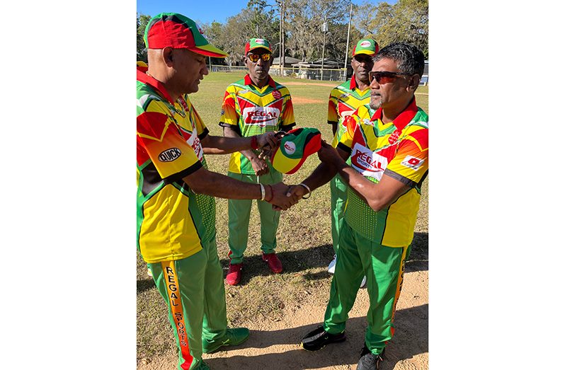 Debutant Khemraj Sumair (right) receives his cap from Regal Legends skipper Mahendra Hardyal before the start of the opening fixture versus OSCL on Friday, a tradition in the Regal camp.