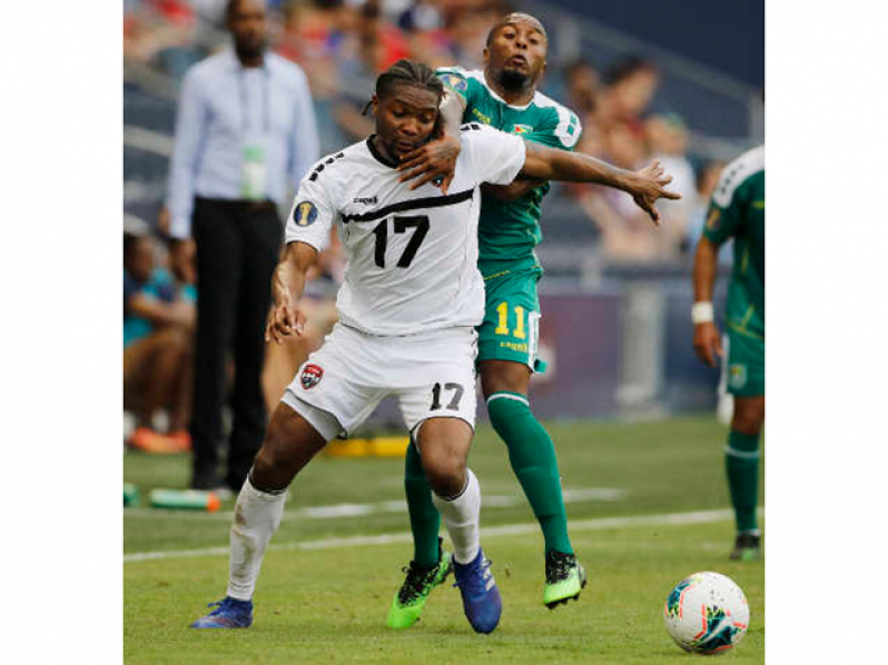 Trinidad and Tobago defender Mekeil Williams is held back by Guyana midfielder Callum Harriott during Gold Cup action on June 26 2019. (Copyright AP photo)